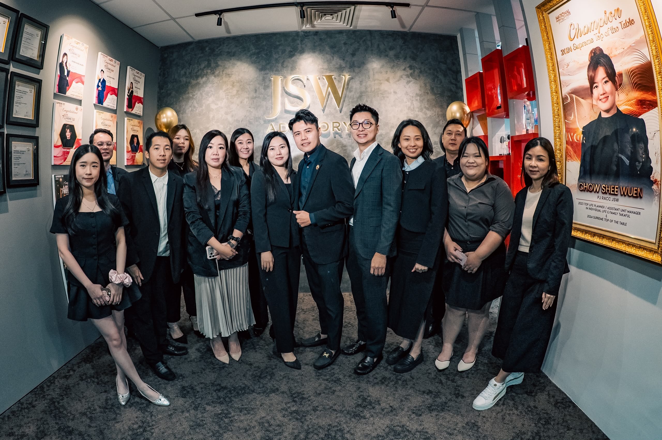 JSW team members gathered in front of the office wall